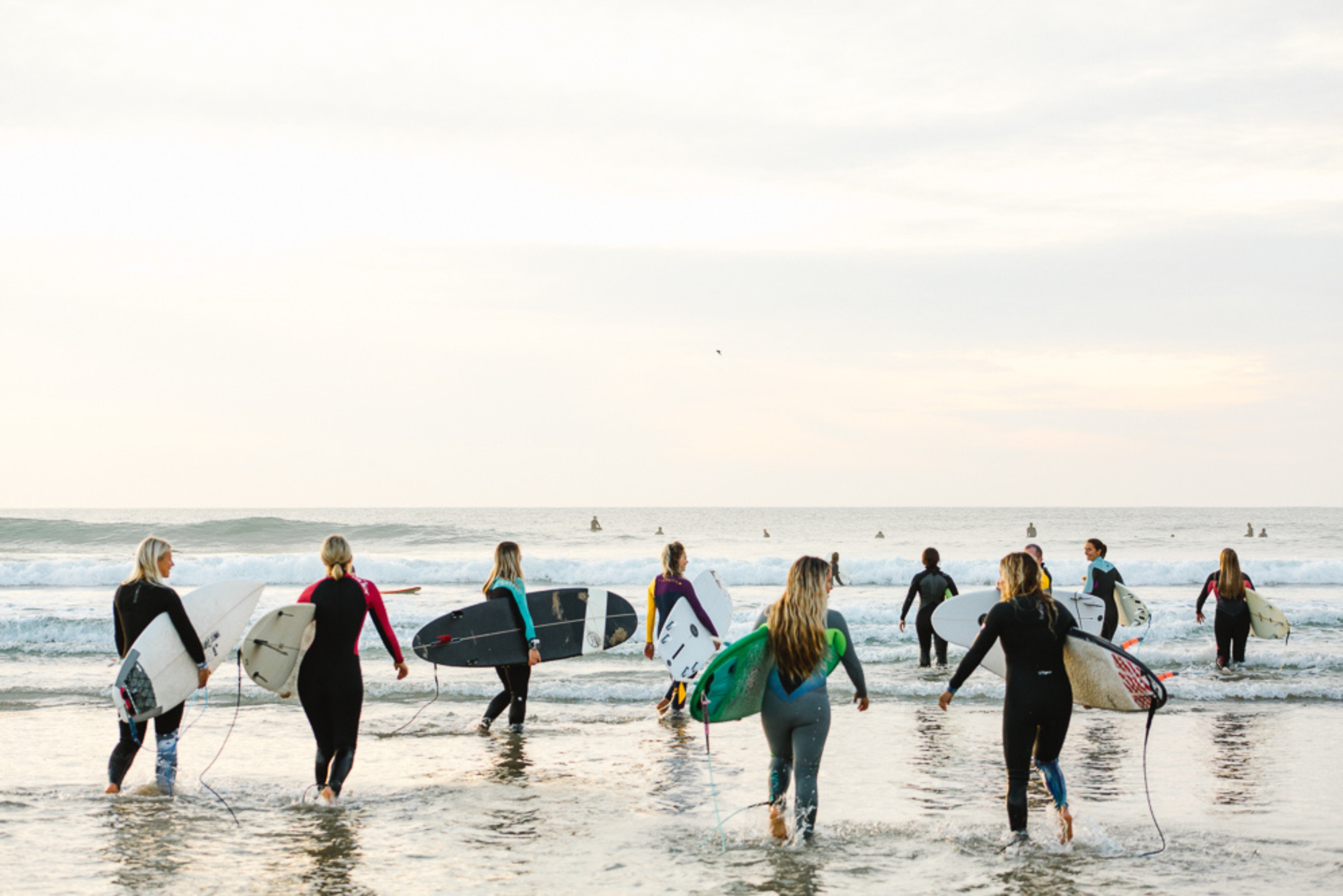 Group of women surfing together in the lineup at Newquay beach Women and Waves