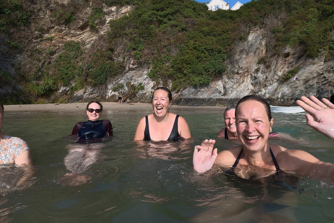 Group of women swimming together in the sea, laughing