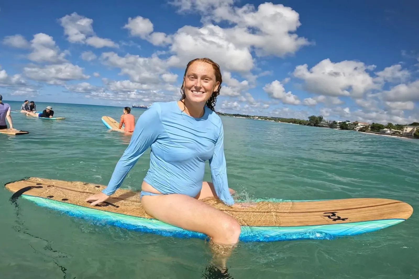 Barbados girl surfer sat on board