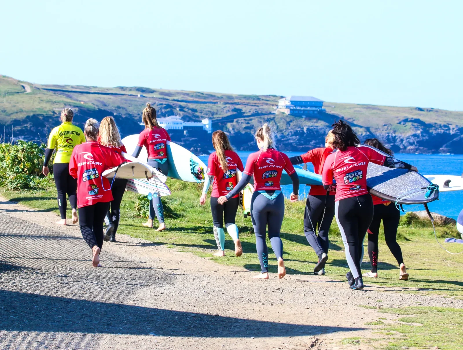 Lady surfers walking holding boards
