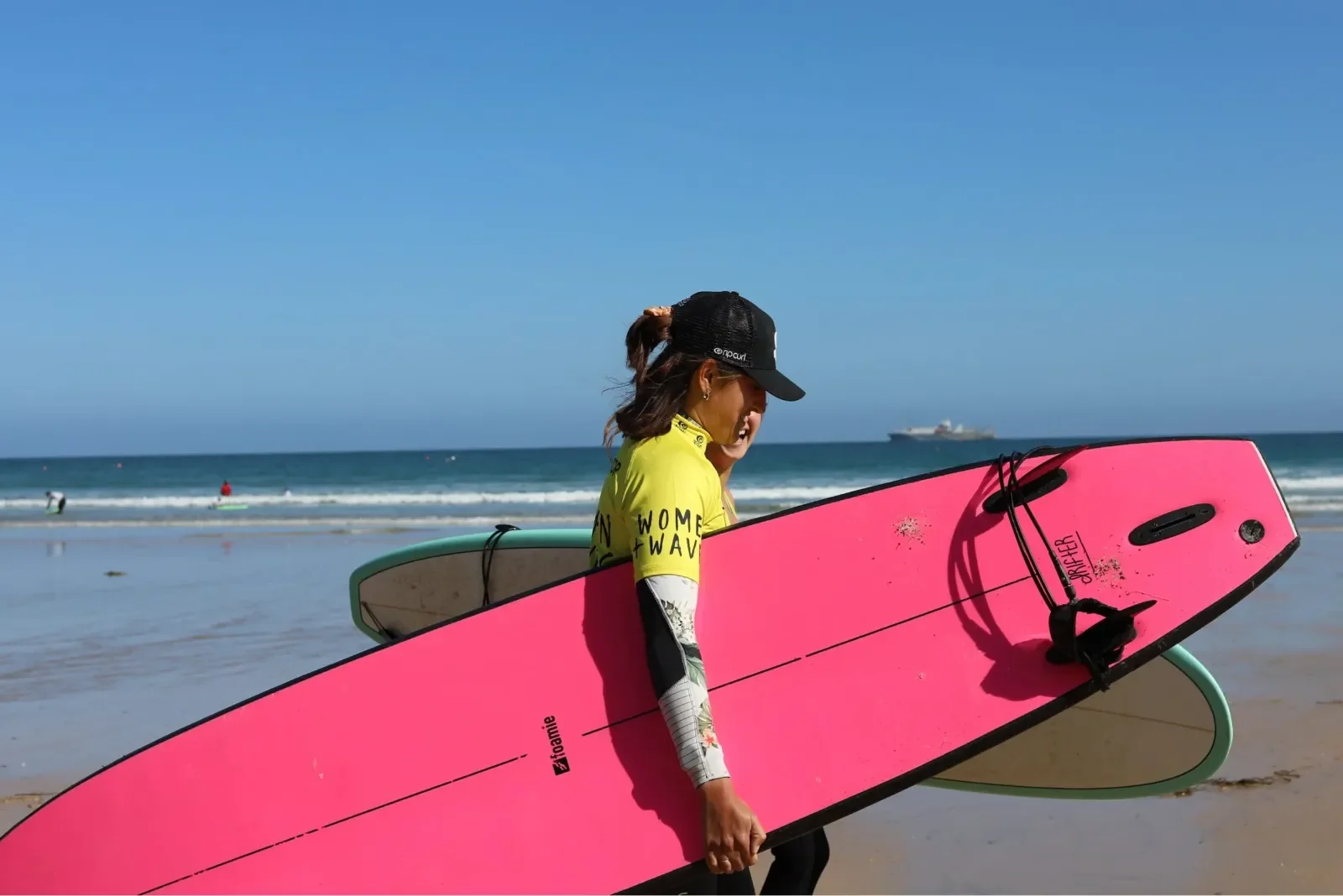 Lady surfer holding pink surfboard